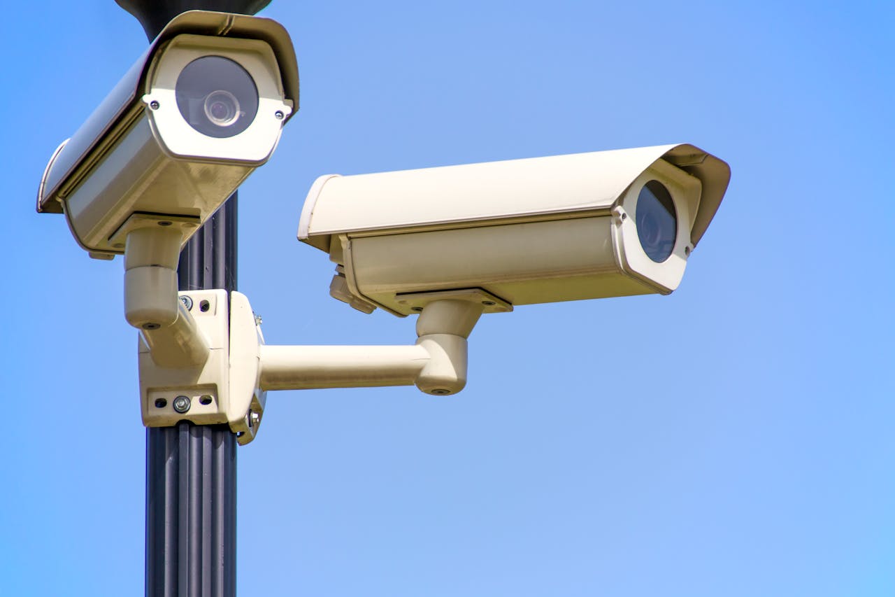 Home 4 Outdoor security cameras mounted on a pole against a clear blue sky, ensuring vigilant surveillance.